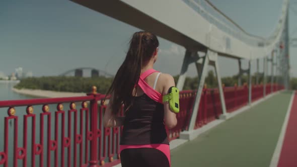 Spoty Athlete Fit Woman Running Along City Bridge