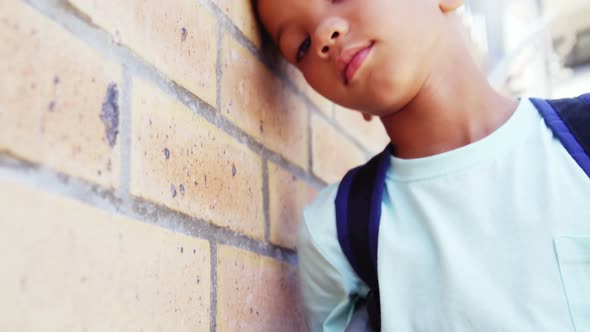 Schoolkid leaning on wall in corridor at school