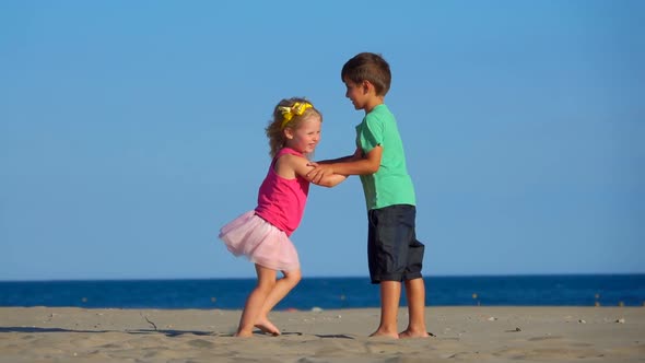 Little Boy and Girl in the Pink Skirt are Playing on the Beach