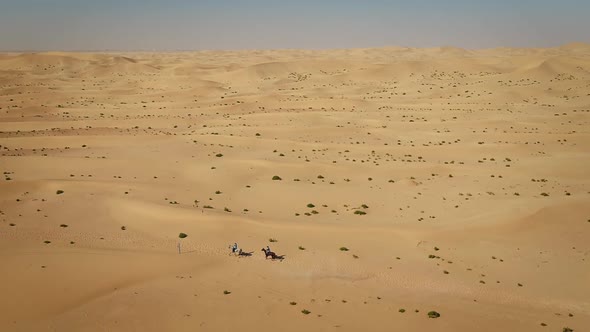 Aerial view of people riding horses in the desert of Al Khatim in Abu Dhabi.