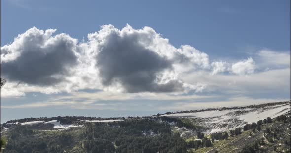 Time Lapse of Cloudscape Behind of the Mountains Top. Snow, Rocks, Cliffs and Deep Blue Sky. High