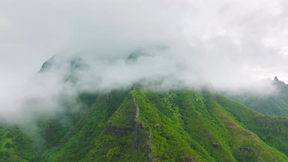 Aerial Shot Flying in the Clouds Covering Green Mountain Peaks on Na Pali Coast