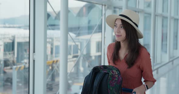 Woman go travel and look out of the window in the airport