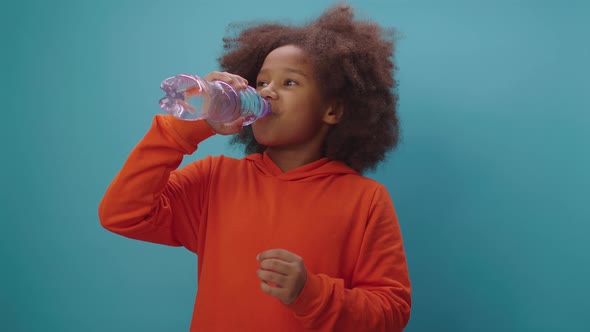 Pretty black girl drinking water holding plastic water bottle in hands