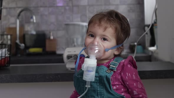 Cute little girl in the mask of an inhaler. Procedure of inhalation at home.