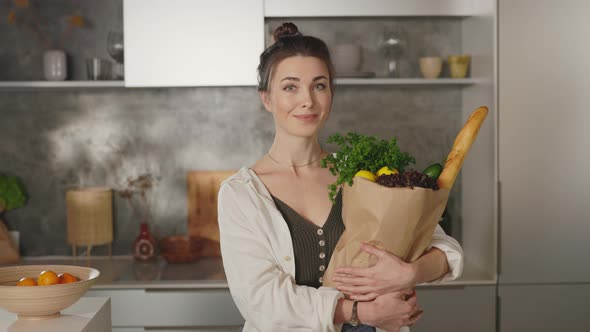 Pleasant Woman Standing on Kitchen with Grocery Bag