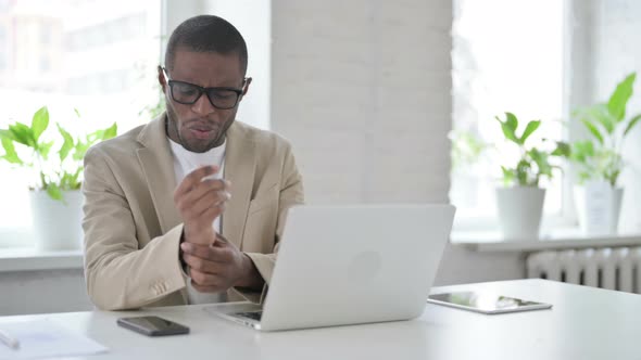 African Man Having Wrist Pain While Using Laptop in Office