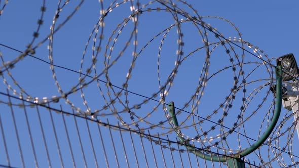 Barbed Wire Hanging on the Border of Iron Fence on Against the Blue Sky