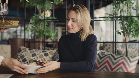 A Young Attractive Woman in a Restaurant is Waiting for Her Order