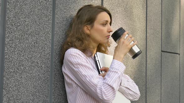 Female Portrait of Young Woman with Silver Laptop and Cup of Coffee Waiting for a Meeting Near Dark