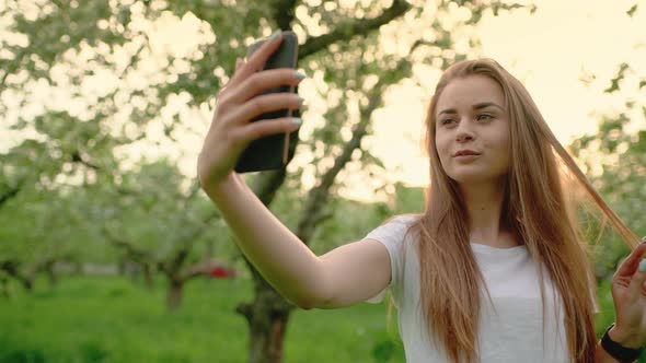 Attractive Blonde Girl Smiling While Taking a Selfie Using a Smartphone