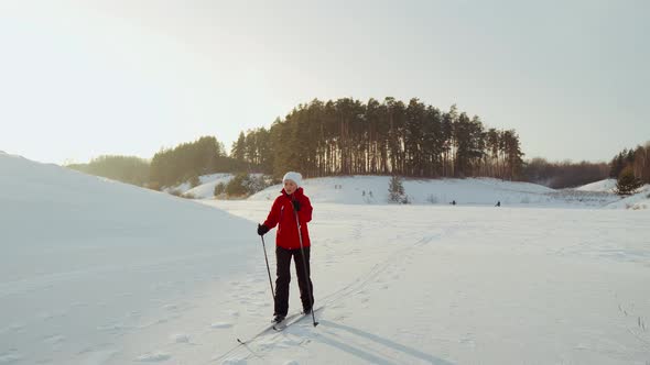 A Woman in a Red Jacket is Skiing on an Icy Lake