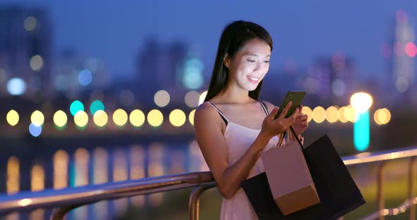 Woman Use of Mobile Phone at Night with Lots of Shopping Bag