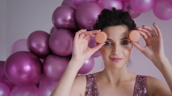 Young Woman in a Purple Dress Puts a Round Cookie