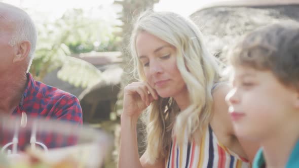 Happy caucasian family having dinner and talking in garden