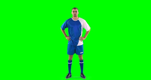 Confident football player standing against green screen