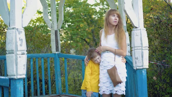 Young Mother Hugs Her Son Standing