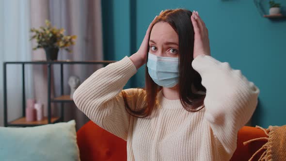 Portrait of Young Sick Girl Wearing Medical Protection Mask Sitting in Living Room Looking at Camera