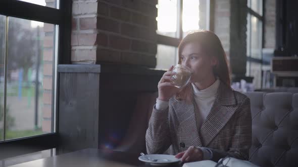 Girl in Cafe, Young Beautiful Woman Enjoys Relaxing at Lunch Time, Drinking Coffee and Looking Out