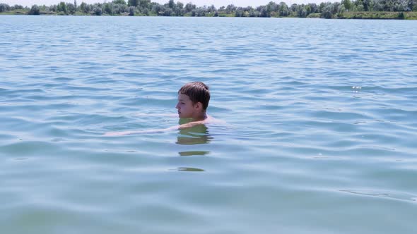 Happy Boy Swimming in Water Enjoys the Rest of the Sea in Rays of Sunlight