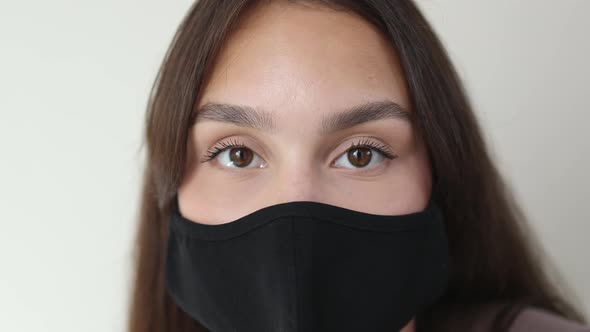 Closeup Big Brown Eyes of Young Brunette Female Black Protective Medical Mask