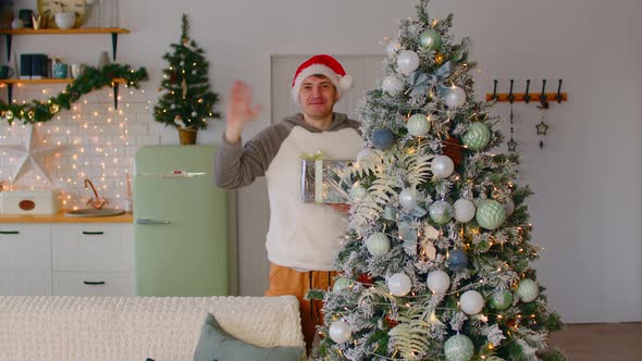 Male Waving Hand Near Xmas Tree