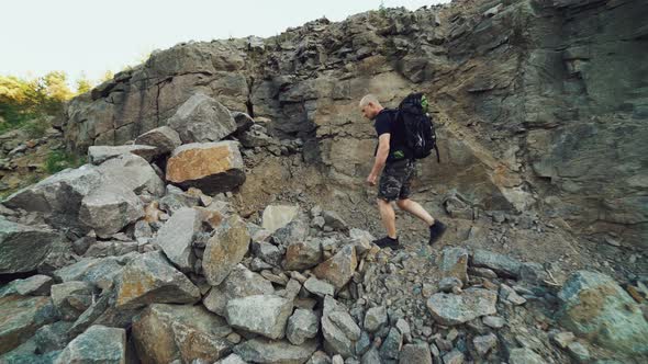 Extreme Tourist with a Backpack on His Shoulders is Walking Along the Rocks