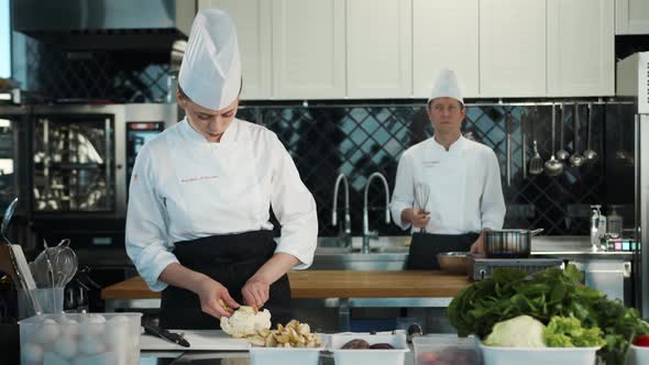 Restaurant Kitchen: Portrait of Male and Female Chefs Preparing Dish. Two Professionals