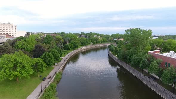 A drone flies over the Flint River in downtown Flint, Michigan at dusk in summer.