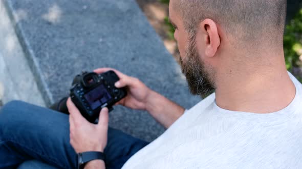 Bearded Photographer Looks at Photos on His Digital Camera