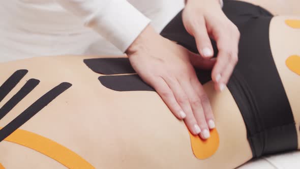 Therapist is applying kinesio tape to female body. Physiotherapy, kinesiology and recovery.