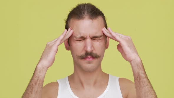 Man in Tshirt Over Yellow Background Trying to Concentrate with Eyes Shut Closeup Concept of