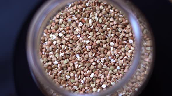 Raw Buckwheat Groats Spinning in a Glass Jar Close Up