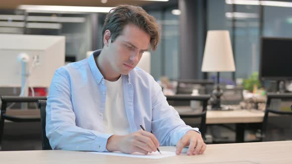 Man Writing on Paper in Office