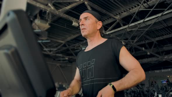 An Athletic Adult Man Runs on a Treadmill Looking in Front of Him