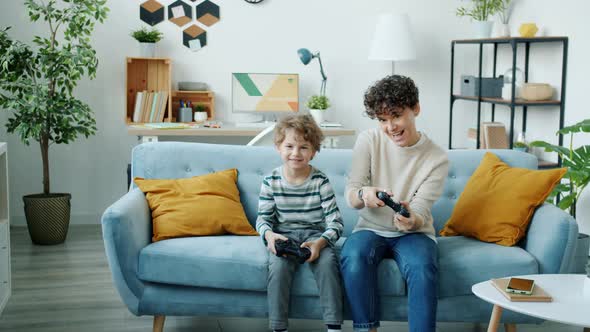 Portrait of Child Playing Video Game with Parent Using Joysticks Having Fun at Home