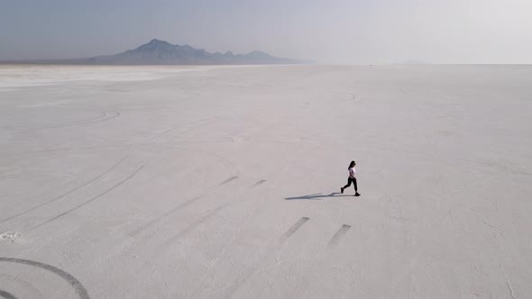 Aerial shot of an Asian woman hiking across the Bonneville Salt Flats flats