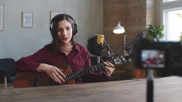Young Female Musician Filming Online Guitar Class in Studio