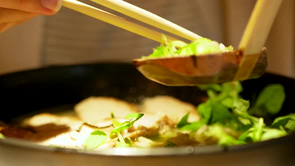 Woman uses chopsticks to eat a bowl of noodle soup.