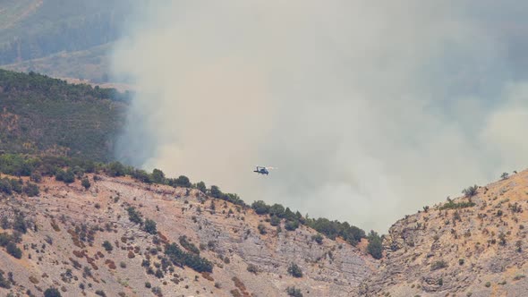 Helicopter flying in front of smoke from forest fire in Utah