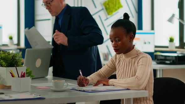 African Businesswoman Analysing Report and Looking at Camera Smiling