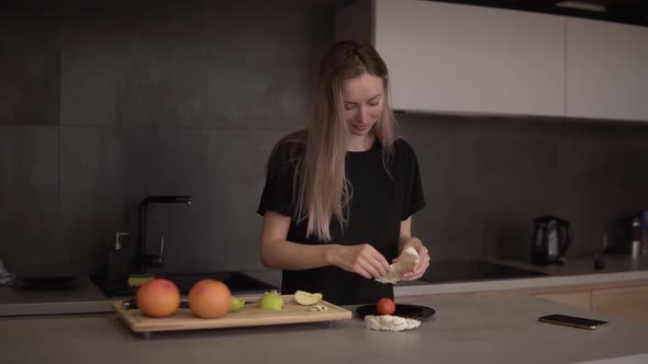 Woman Cleans Pomelo Slice in the Kitchen on a Counter
