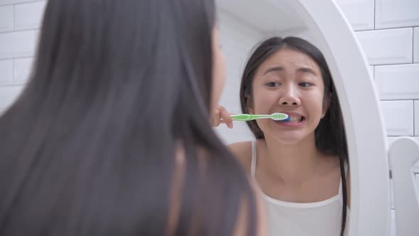 Daily routine concept. Asian woman brushing teeth in the bathroom. 4k Resolution.