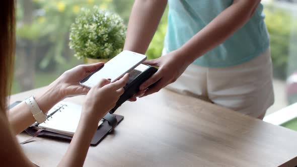 Young woman sitting near glass window use smartphone payment