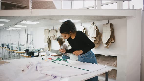 Sewing Workshop Mixed Race Seamstress Taking Measurements of Fabric By Tape Measure Colleague