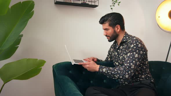 Handsome Focused Fashionable Cuban Man Sitting on a Sofa Typing on His Computer