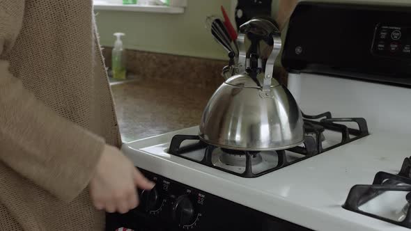 Close view of woman lighting stove for teapot