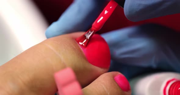 The Pedicure Master Applies Red Polish on the Toe