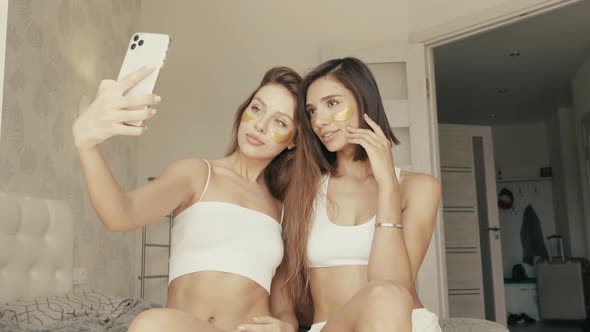 Two young beautiful smiling women with patches under their eyes posing indoors