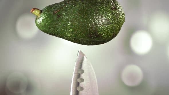 Fresh Avocado Falling Down with Drop on Knife Stuck